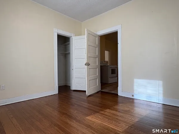 a view of an empty room with wooden floor and closet