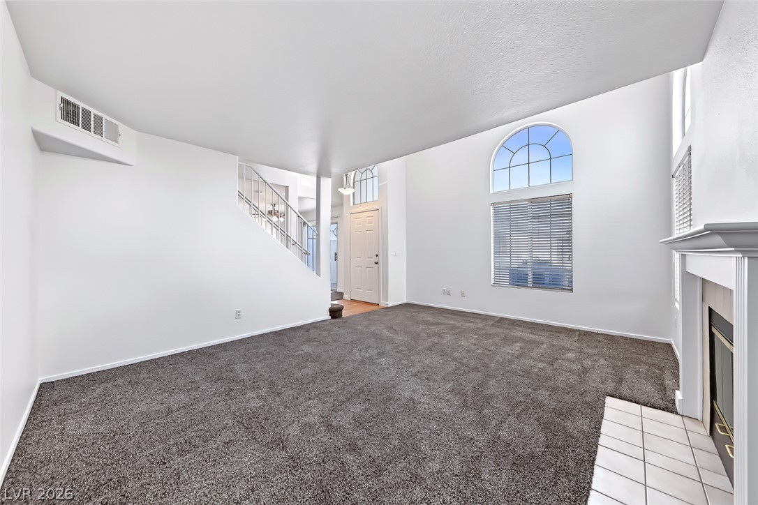 205 Genesee Point Street Henderson, NV 89074 - Photo 8 of 30 Soaring ceilings and arched windows frame a welcoming hearth in this carpeted living room.