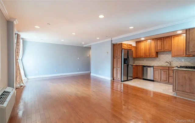 a view of kitchen with kitchen island granite countertop wooden floor stainless steel appliances and window