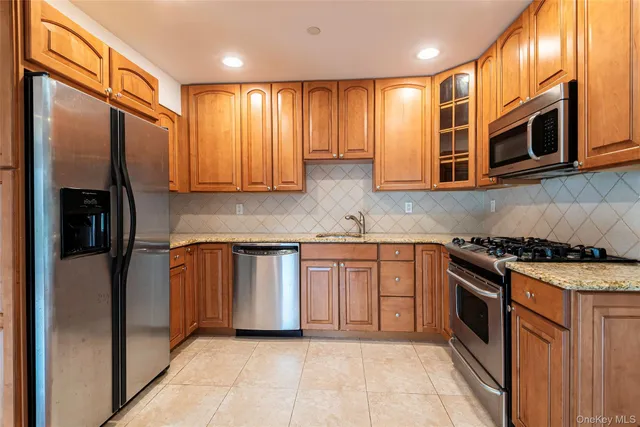 a kitchen with stainless steel appliances granite countertop wooden cabinets a stove top oven a sink and dishwasher