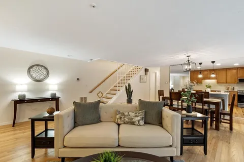 a living room with furniture kitchen area and a chandelier