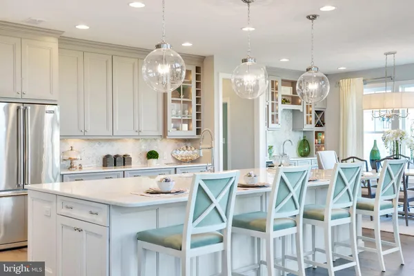a kitchen with stainless steel appliances kitchen island granite countertop a dining table chairs and white cabinets