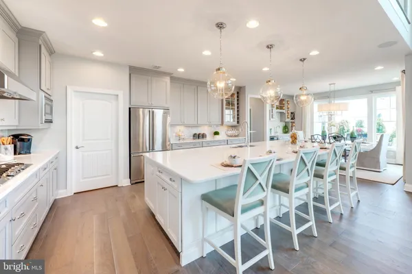 a kitchen with stainless steel appliances kitchen island granite countertop a dining table chairs and white cabinets