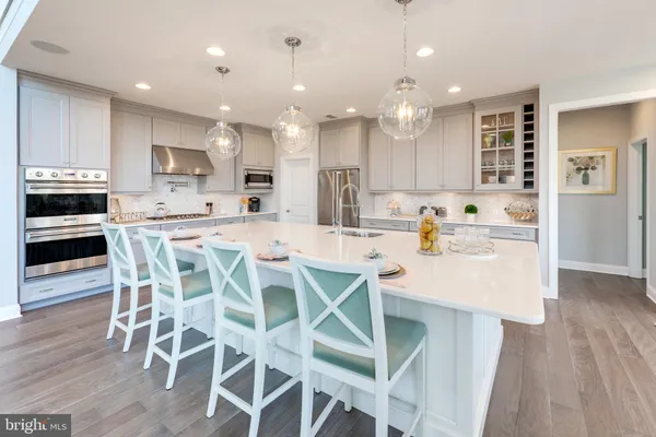 a kitchen with stainless steel appliances kitchen island granite countertop a dining table chairs and sink