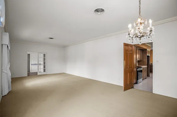 an empty room with chandelier and glass door
