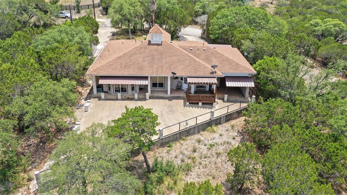 an aerial view of a house with swimming pool and large trees