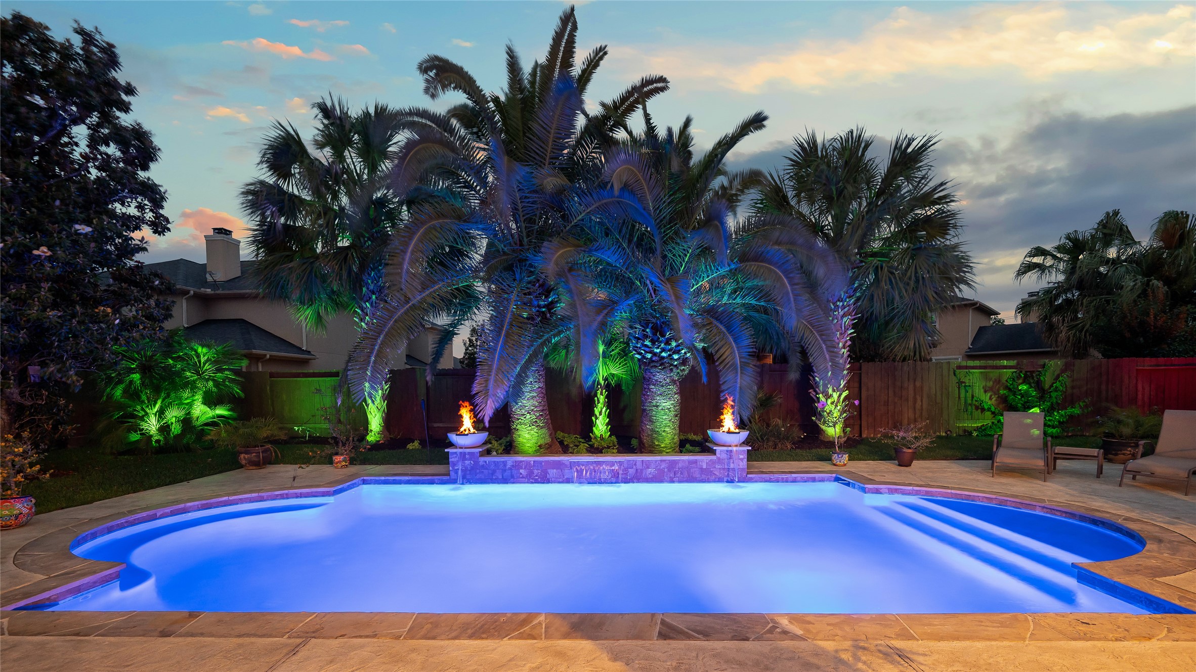 2127 Thicket Ridge Lane Houston, TX 77077 - Photo 34 of 48 A breathtaking aquatic stage: sculptural fire-and-water features (2025) flicker against a silhouette of majestic, mature palms. The grounds are transformed at dusk by a professional Luxor ZDC lighting system—a masterclass in atmospheric design. With 32 independent zones and a palette of 32,000 colors at your fingertips, you can curate a bespoke evening experience, from a tranquil moonlit glow to a vibrant resort spectacle.