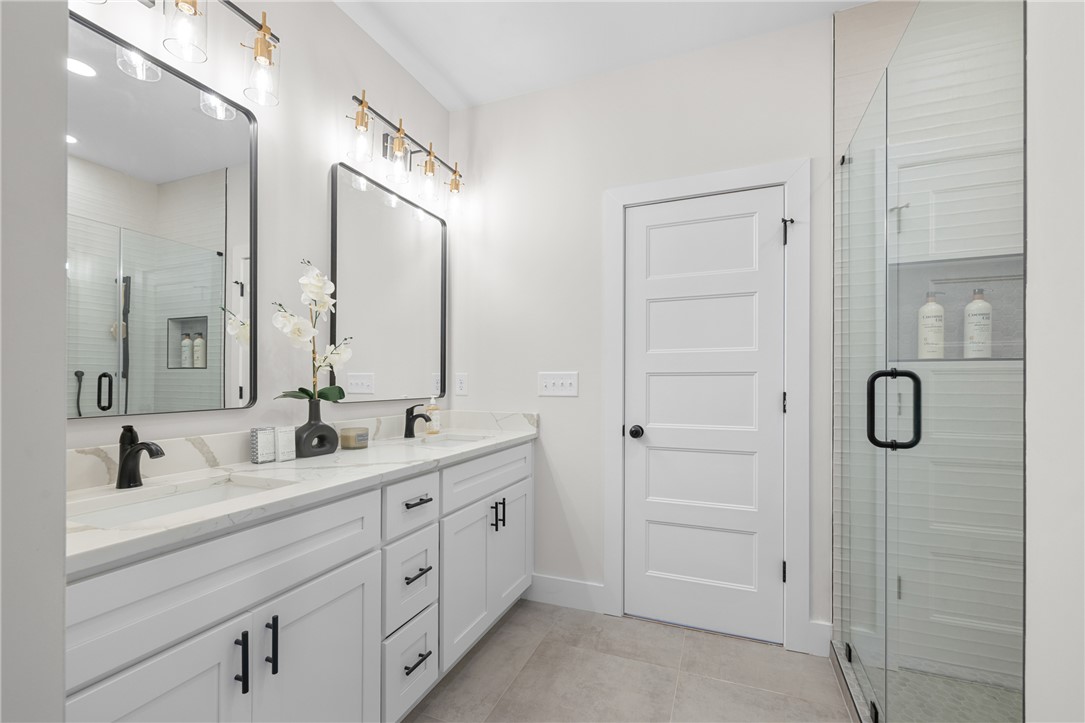 502 Point Road Westminster, SC 29693 - Photo 23 of 49 Dual vanities with sleek black fixtures and a glass-enclosed shower create a pristine and functional primary bathroom.