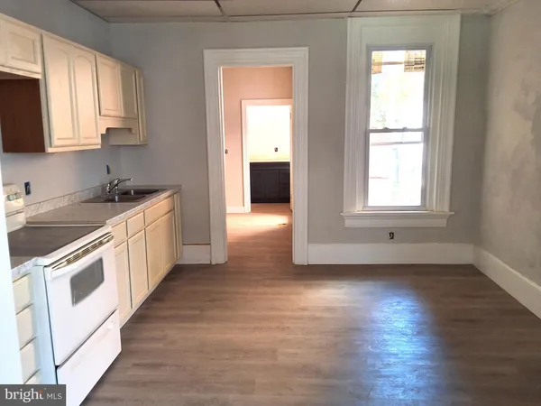 a kitchen with a white cabinets and wooden floor
