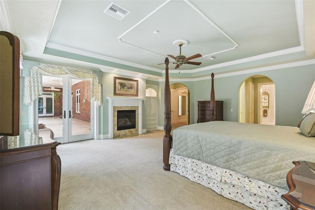 1745 Taylor Woods Road DeLand, FL 32724 - Photo 39 of 66 a spacious bedroom with a large bed a chandelier and fireplace