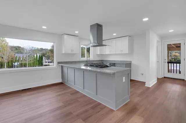 a kitchen with stainless steel appliances granite countertop a stove a sink and a large wooden floors