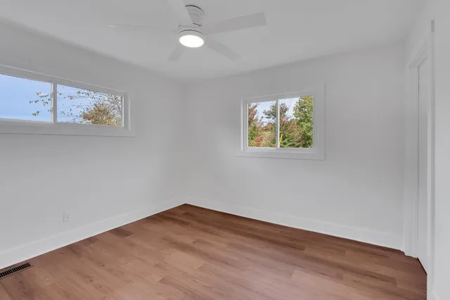 an empty room with wooden floor and windows