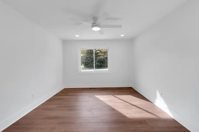 an empty room with wooden floor and windows