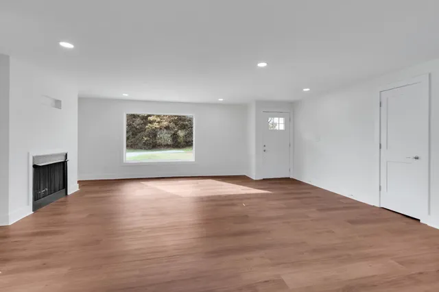 an empty room with wooden floor and fireplace