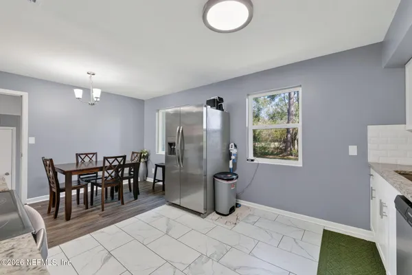 a open kitchen with stainless steel appliances granite countertop a stove top oven a sink dishwasher a dining table and chairs with wooden floor