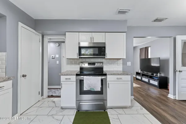 a kitchen with stainless steel appliances granite countertop a sink dishwasher stove top oven and cabinets