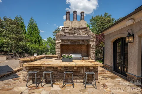 a view of patio with table and chairs under an umbrella with a barbeque