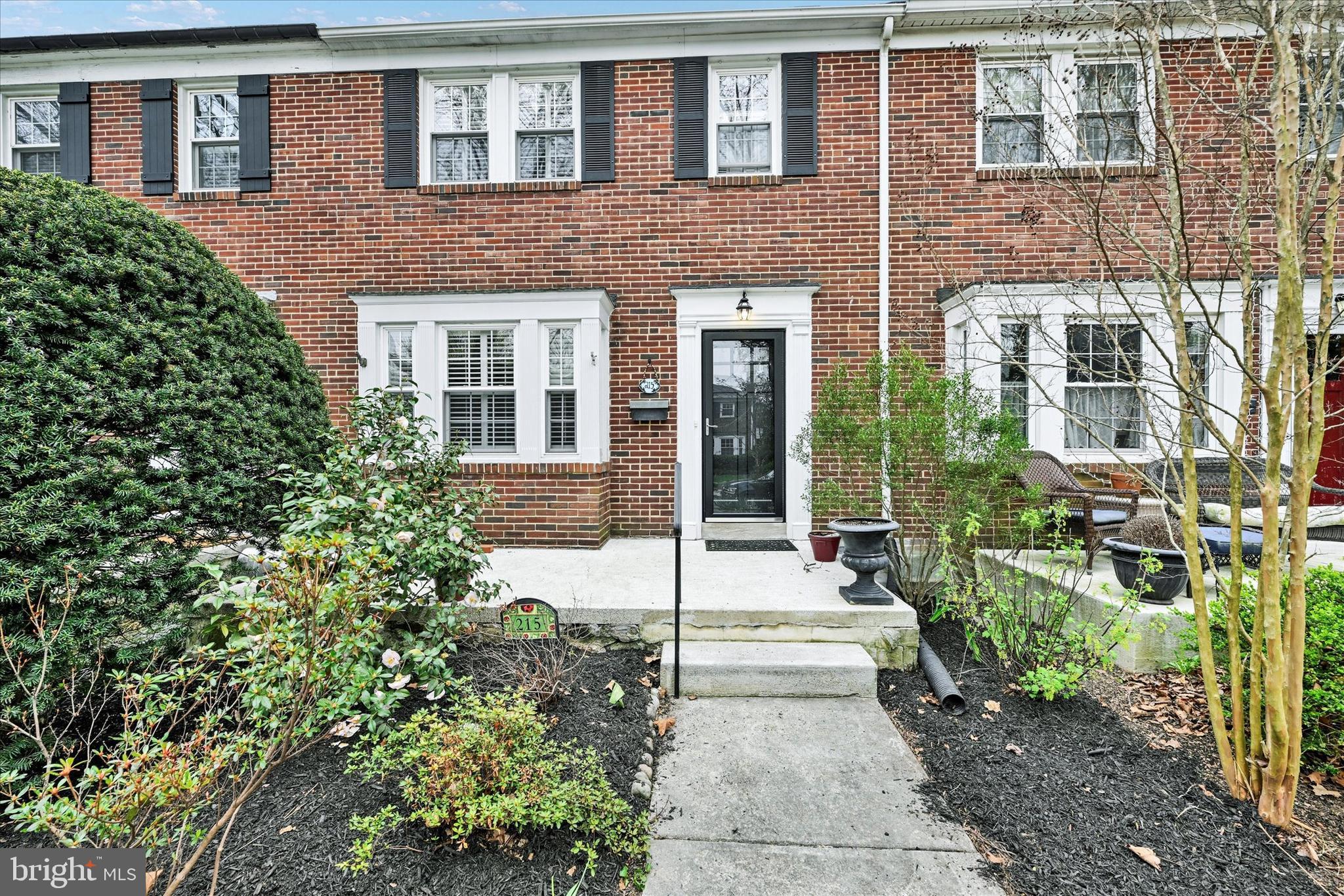 a view of a brick house with a yard and plants