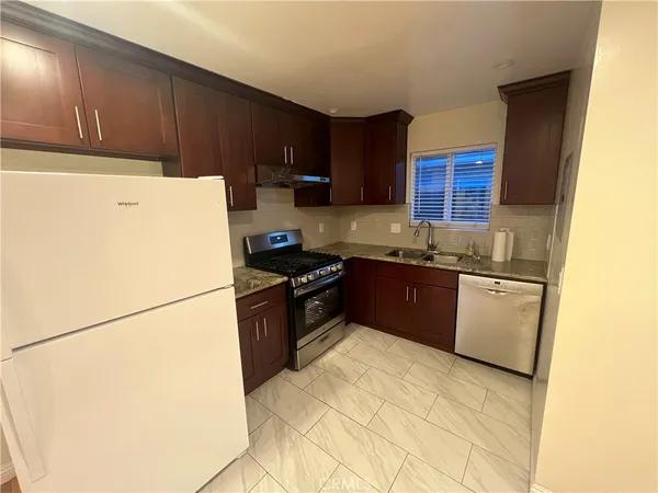 a kitchen with a refrigerator a stove top oven a sink and cabinets