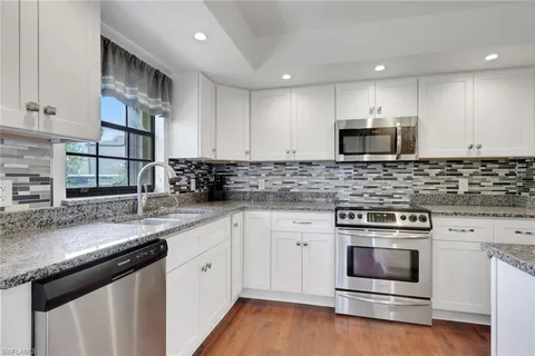 a kitchen with stainless steel appliances granite countertop a stove a sink and a microwave