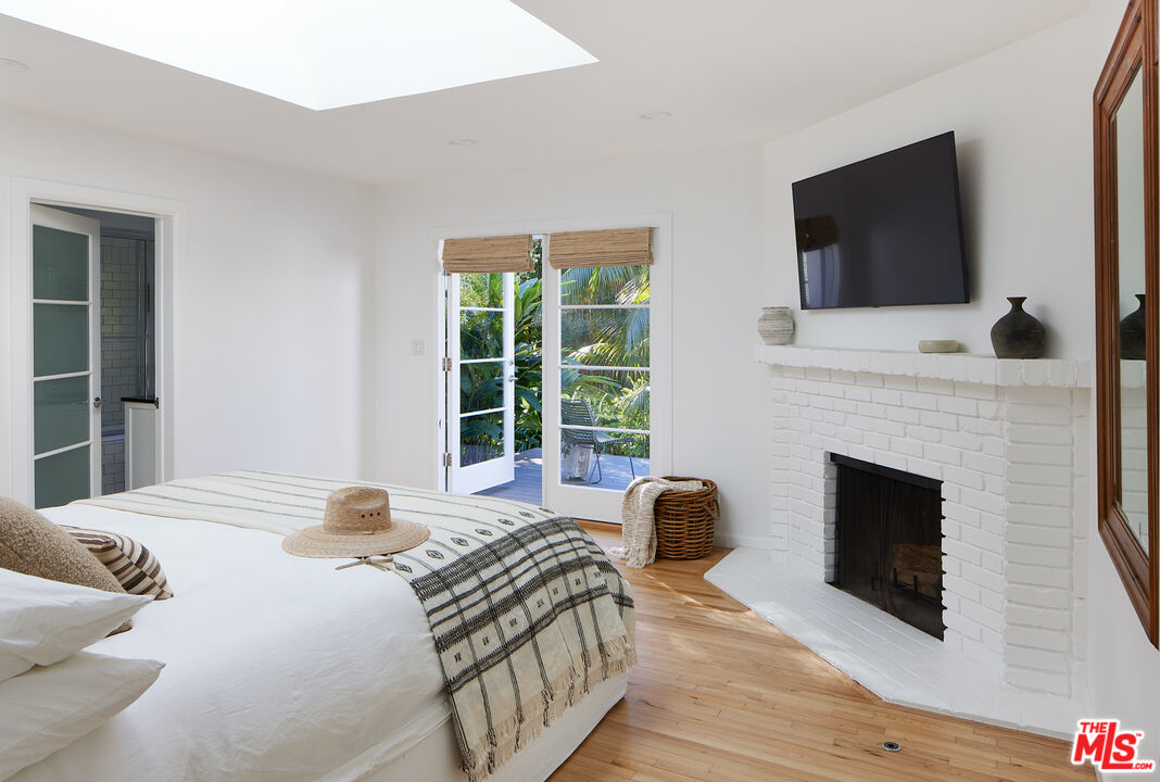6637 Zumirez Drive Malibu, CA 90265 - Photo 9 of 29 a bedroom with a bed a flat screen tv and a fireplace