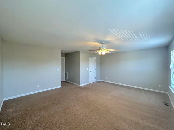 a view of an empty room with a chandelier fan