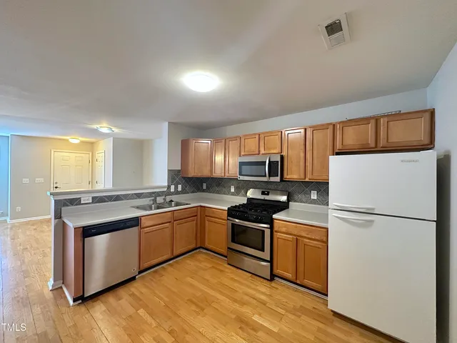 a kitchen with stainless steel appliances granite countertop a stove a refrigerator a sink and a refrigerator