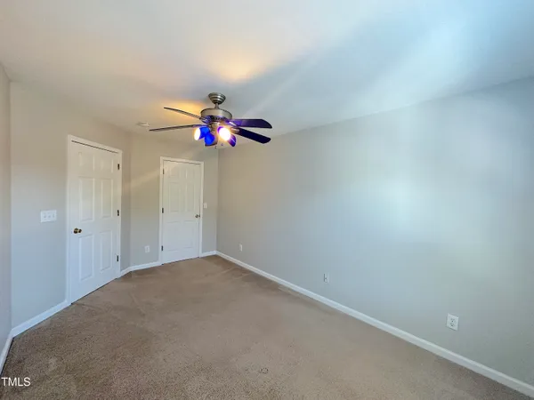 an empty room with a chandelier fan and a window