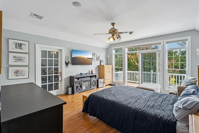 a bedroom with a large bed a flat tv screen and a dresser