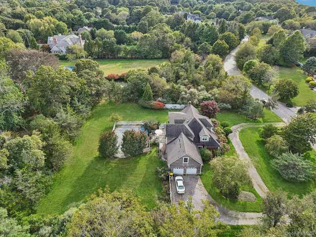 an aerial view of a houses with outdoor space and trees all around
