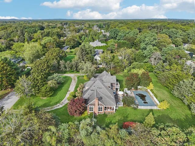 an aerial view of residential house with outdoor space and trees all around