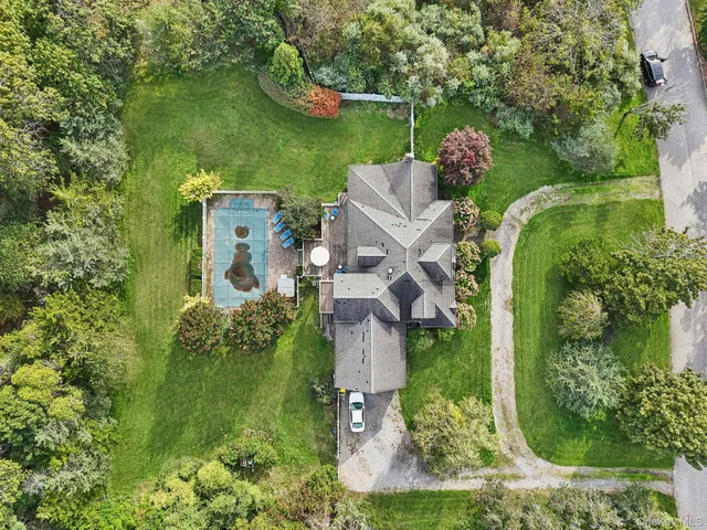 an aerial view of a house with outdoor space and trees all around