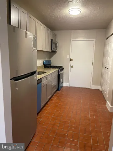 a kitchen with stainless steel appliances granite countertop a refrigerator a stove a sink and a refrigerator