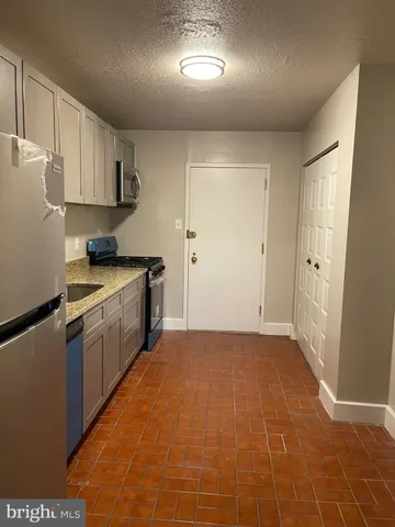 a kitchen with granite countertop a sink a counter top space stainless steel appliances and cabinets