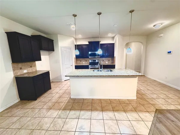 a large kitchen with stainless steel appliances kitchen island granite countertop a sink a stove a counter top space and cabinets