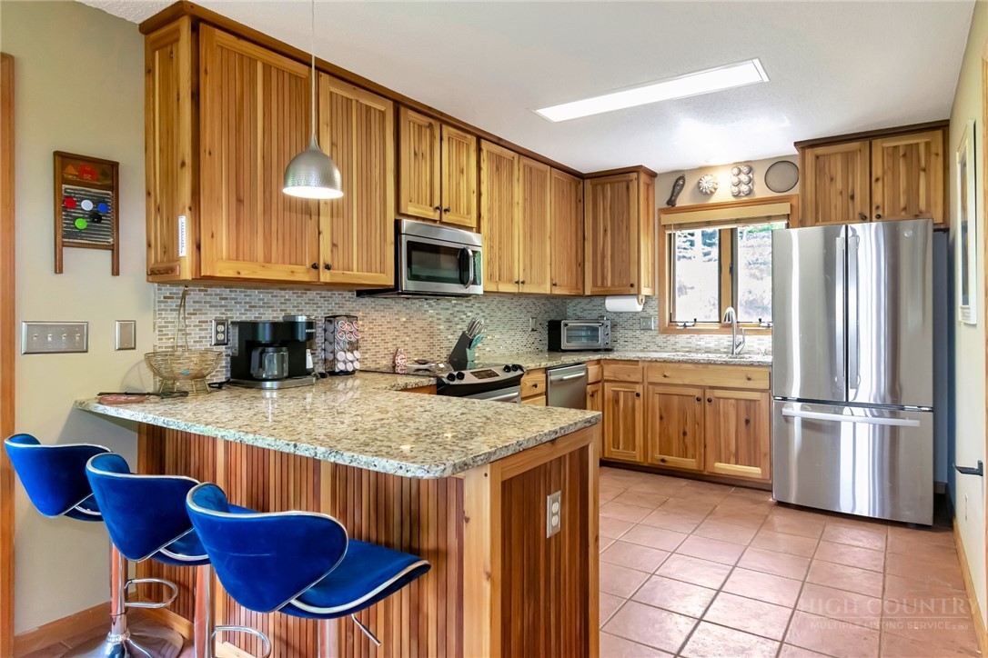 1078 Charter Hills Road Beech Mountain, NC 28604 - Photo 6 of 50 a kitchen with stainless steel appliances granite countertop a stove a sink dishwasher and a refrigerator with wooden cabinets