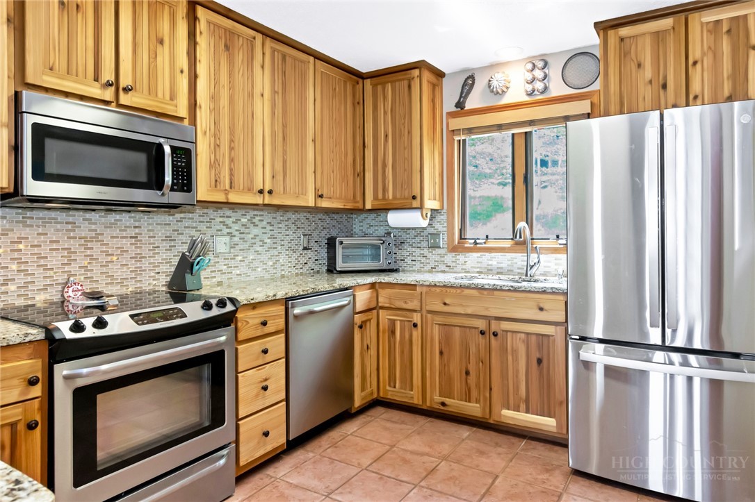 1078 Charter Hills Road Beech Mountain, NC 28604 - Photo 7 of 50 a kitchen with granite countertop a stove top oven microwave and refrigerator