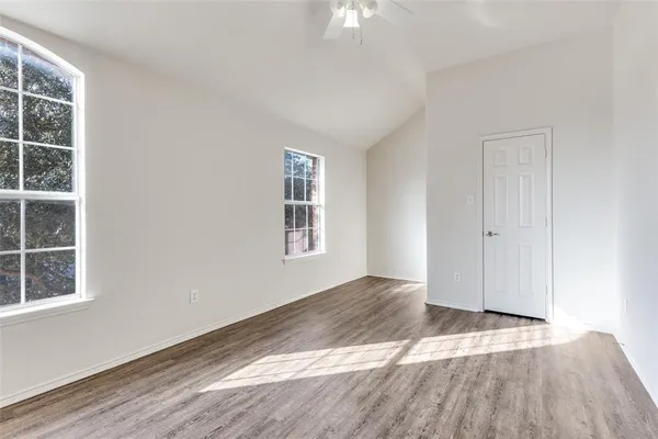 an empty room with wooden floor and windows