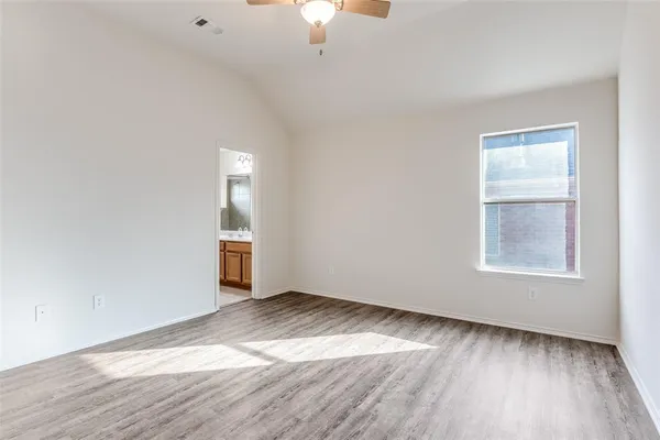an empty room with wooden floor cabinet and windows