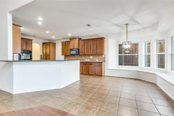 a large white kitchen with granite countertop a stove top oven a sink a counter top space and cabinets