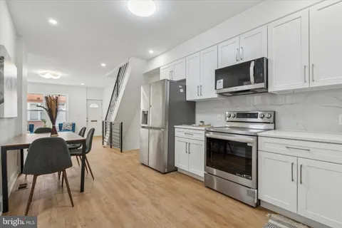 a kitchen with stainless steel appliances a stove a microwave a sink a refrigerator and white cabinets