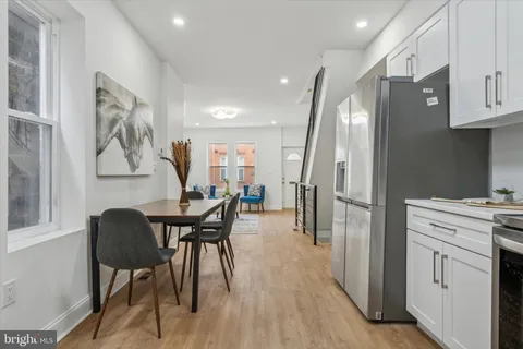 a kitchen with stainless steel appliances granite countertop a dining table chairs refrigerator and sink