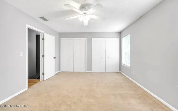 a view of a big room with windows and chandelier fan