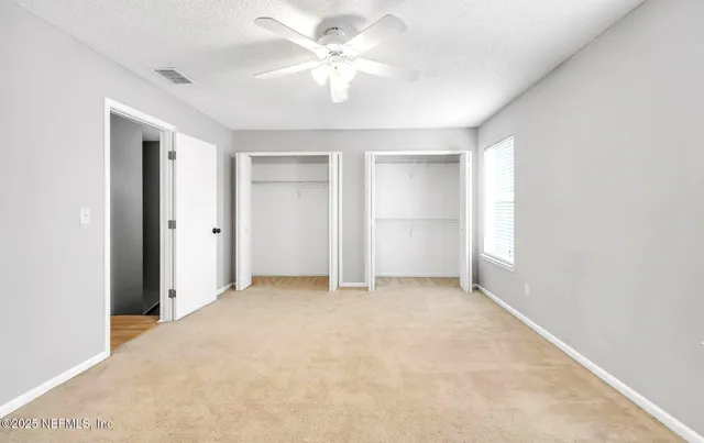 an empty room with closet and a ceiling fan