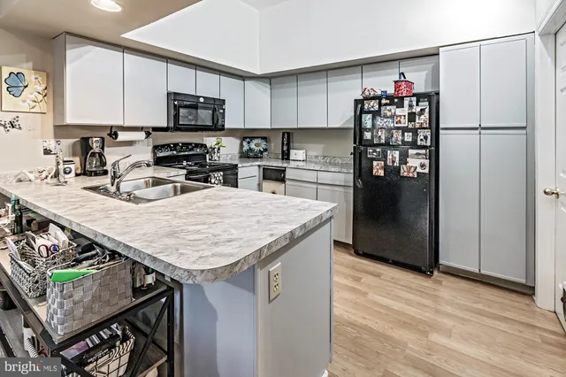 a kitchen with stainless steel appliances granite countertop a refrigerator a stove a sink dishwasher and microwave with wooden floor