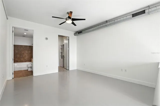 an empty room with wooden floor fan and windows