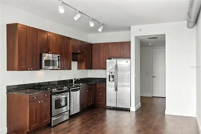 a large kitchen with stainless steel appliances granite countertop a stove a sink and a refrigerator