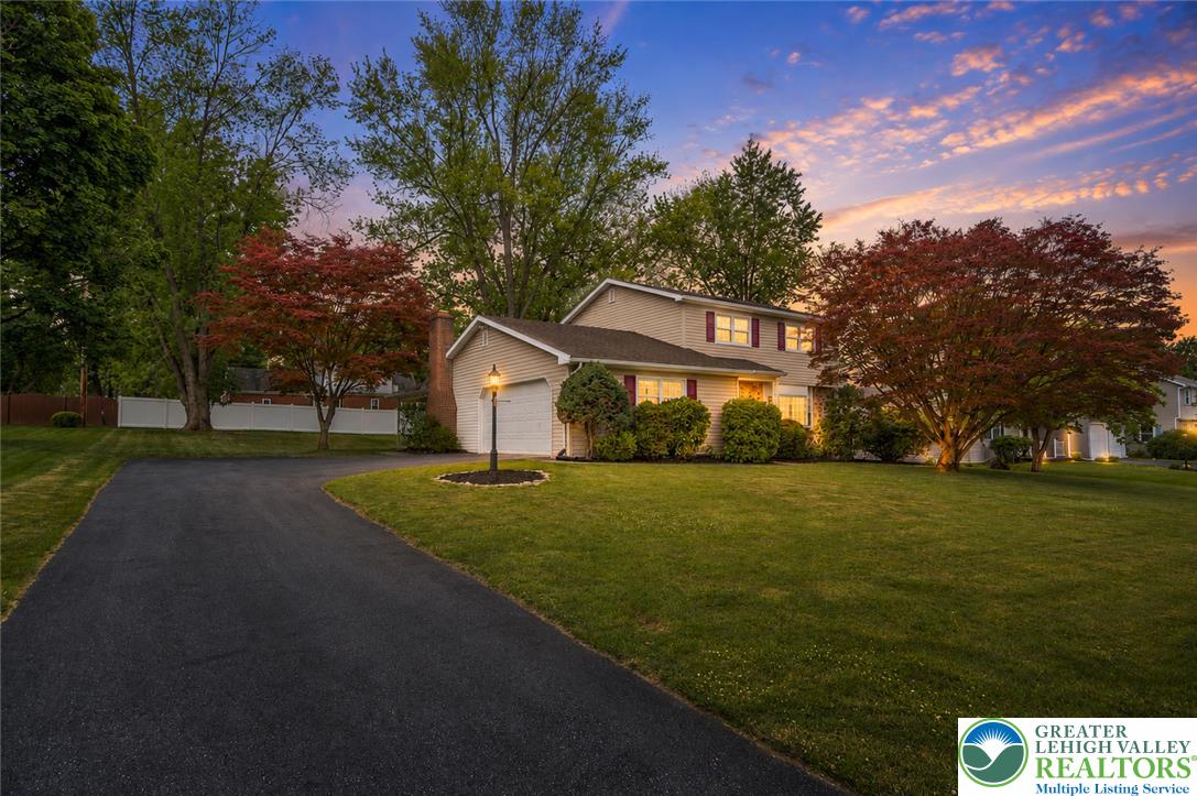 268 Apollo Drive Bethlehem, PA 18017 - Photo 45 of 56 A welcoming front exterior with mature trees and a long driveway under a vibrant sunset sky.