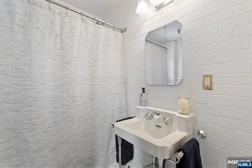 294 Sylvan Street Rutherford, NJ 07070 - Photo 19 of 29 a bathroom with a sink a mirror and shower curtain