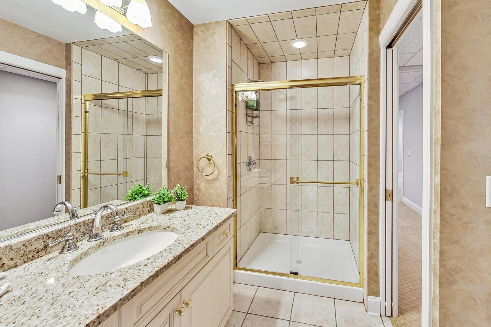 4454 Kettering Drive Long Grove, IL 60047 - Photo 32 of 44 a bathroom with a granite countertop sink a mirror a glass door and shower